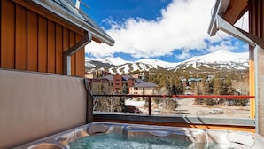 Un jacuzzi con vistas a montañas nevadas y edificios.