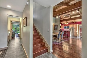 Un interior moderno con una escalera de madera, un comedor y una cocina con una pared de acento roja.