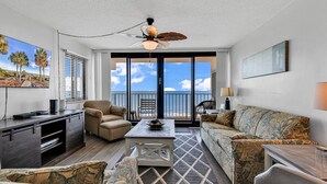 A spacious living area with a balcony overlooking the ocean, a ceiling fan, and a large painting of a beach scene. - *20% Off New Summer 2026 Bookings* (Garden City)