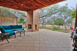 Une terrasse extérieure avec une cheminée en briques, un canapé bleu et un barbecue.