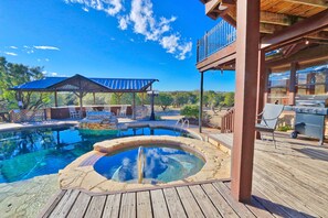 Un espace piscine comprenant un jacuzzi, une terrasse en bois et des sièges d’extérieur.