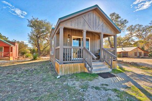 A wooden cabin with a porch and steps leading to a door.