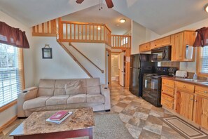 A spacious living room with a beige sofa, a coffee table, and a staircase leading to an upper level. - Amazing Ranch Sleeps 42 Plus! Located On 75 Acres With A Pool And Barn (Wimberley)