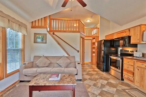 A spacious living area with a sofa, a coffee table, and a kitchen with wooden cabinets and appliances. - Amazing Ranch Sleeps 42 Plus! Located On 75 Acres With A Pool And Barn (Wimberley)