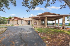 A stone house with a covered patio and a paved driveway. - On Top of the World  I Minutes from beautiful Canyon Lake (Wimberley)