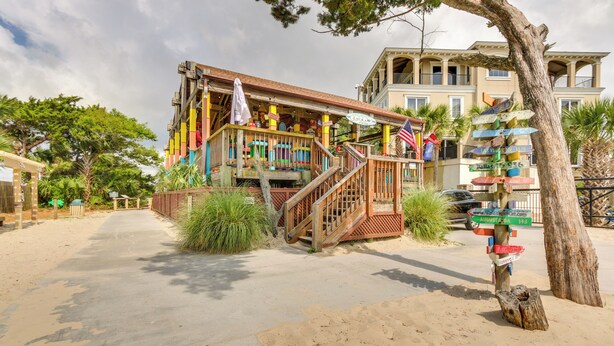 A colorful building with a wooden staircase and a signpost with multiple directions. - Walk to Beach: Hilton Head Resort Condo w/ Pools! (Hilton Head Island)