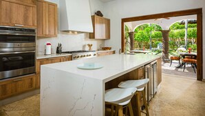 Une cuisine moderne avec des meubles en bois, des appareils en acier inoxydable et un grand îlot central doté de tabourets de bar.