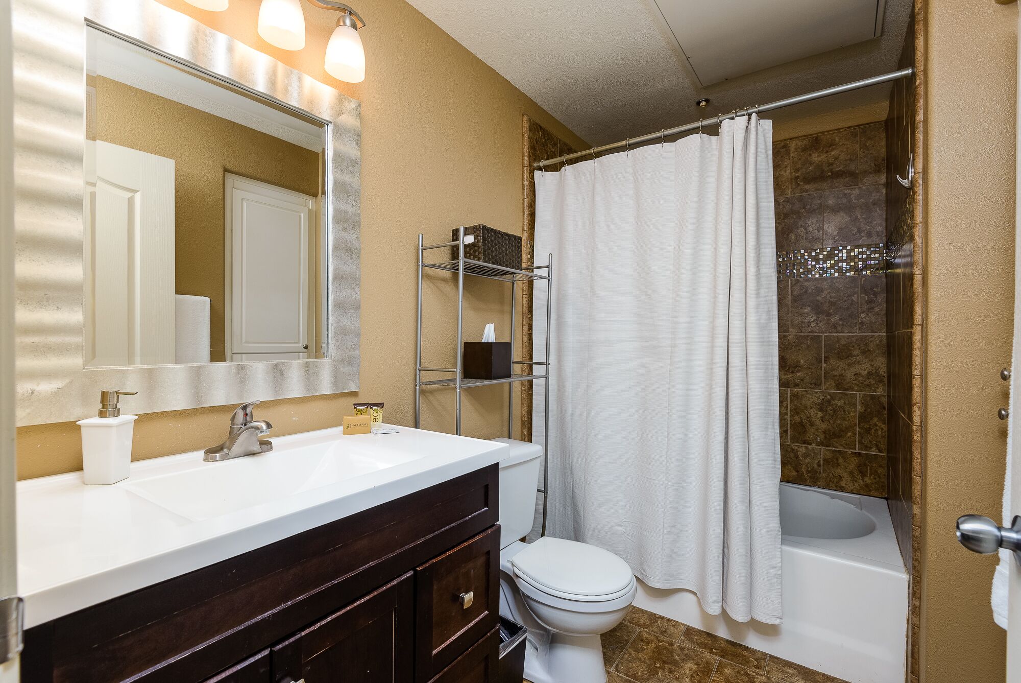 Une salle de bain avec un lavabo blanc, un miroir, des toilettes et une baignoire.