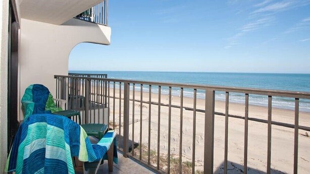 A balcony with a view of the beach and ocean.