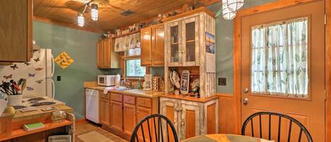 A rustic kitchen with wooden cabinets, a dining table with chairs, and a refrigerator.