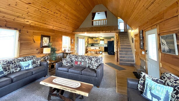 A log cabin interior with a living room, dining area, kitchen, and staircase. - Loose Moose @ Spring Brook Resort (Wisconsin Dells)