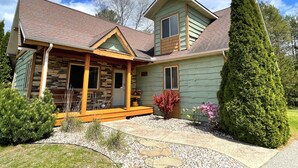 A two-story house with a stone facade, a wooden porch, and a well-maintained garden. - Loose Moose @ Spring Brook Resort (Wisconsin Dells)