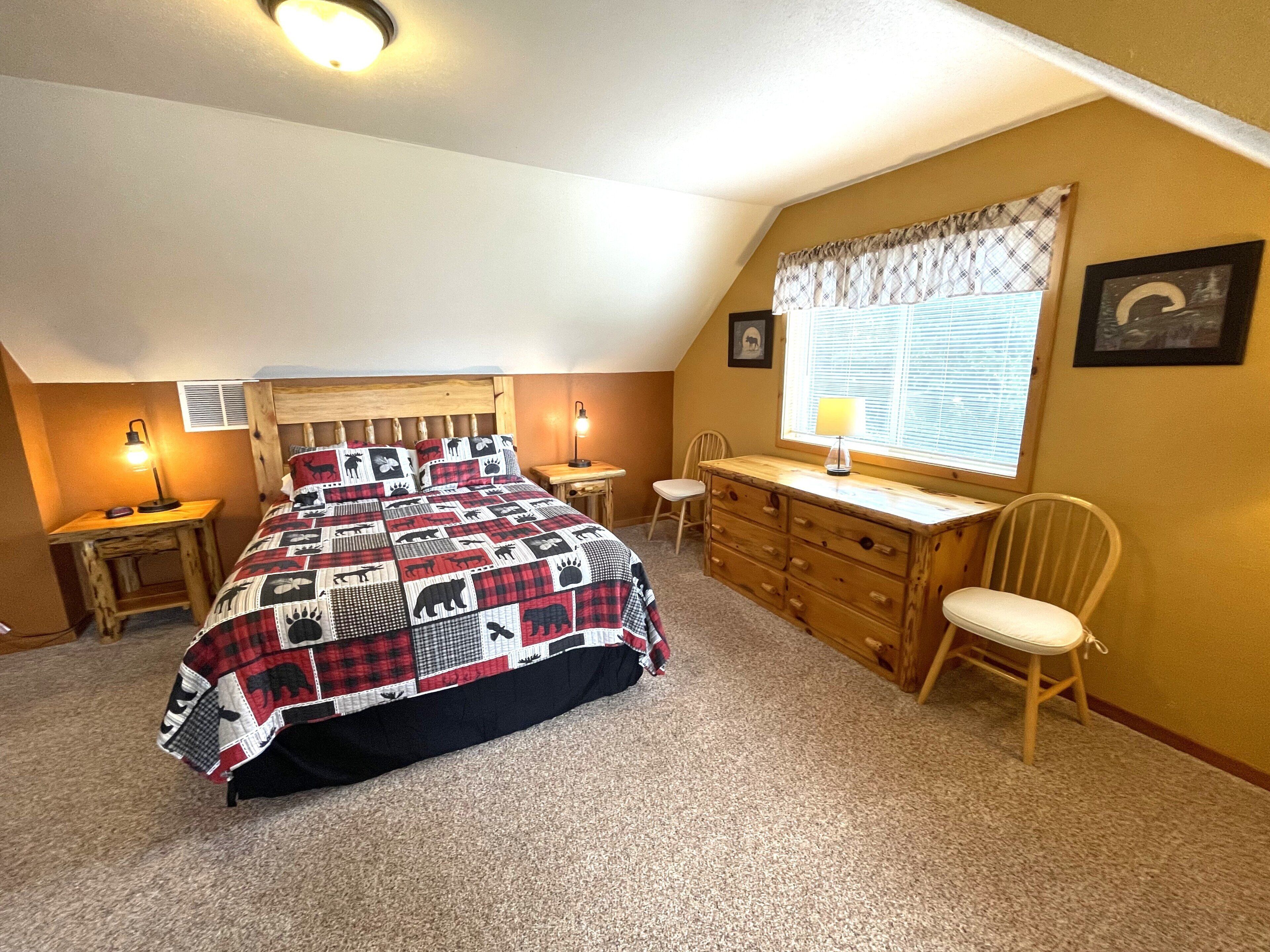 Une chambre à coucher comprenant un lit, un bureau, une chaise, une commode et une fenêtre avec des stores.