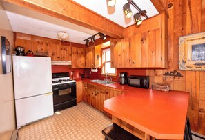 A kitchen with wooden cabinets, a refrigerator, stove, sink, and a microwave.