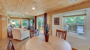 Un intérieur en bois comprenant une table à manger, des chaises, un canapé et une vue sur l’extérieur.