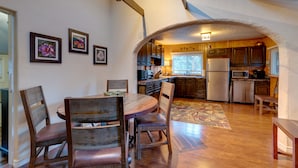 A kitchen with wooden cabinets, a dining table with chairs, and a refrigerator. - Rustic Log Cabin w/ Studio ~ 5 Mi to Pikes Peak! (Green Mountain Falls)