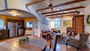 A spacious kitchen with wooden beams, a dining area with a round table, and a living room with a sofa and armchairs. - Rustic Log Cabin w/ Studio ~ 5 Mi to Pikes Peak! (Green Mountain Falls)