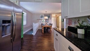 A kitchen with a stainless steel refrigerator, wooden dining table, and white cabinets. - LAST MINUTE DEAL, Charming Elevated Duplex – Relaxing Beach Getaway Near Anna Maria Island- Bay access (Bradenton)