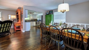 A dining area with a wooden table and chairs, a chandelier, and a view into the kitchen. - LAST MINUTE DEAL, Charming Elevated Duplex – Relaxing Beach Getaway Near Anna Maria Island- Bay access (Bradenton)