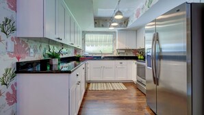 A kitchen with white cabinets, a stainless steel refrigerator, and a window with blinds. - LAST MINUTE DEAL, Charming Elevated Duplex – Relaxing Beach Getaway Near Anna Maria Island- Bay access (Bradenton)