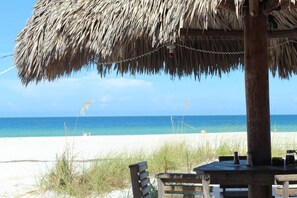 A beachside restaurant with a thatched roof, wooden tables, and chairs, overlooking a sandy beach and the ocean. - LAST MINUTE DEAL, Charming Elevated Duplex – Relaxing Beach Getaway Near Anna Maria Island- Bay access (Bradenton)