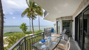 A balcony with a glass table, chairs, and a view of the ocean and palm trees. - Mar Y Sol –Luxurious oceanfront  Key West Breathtaking Atlantic Sunrise Views (Key West)