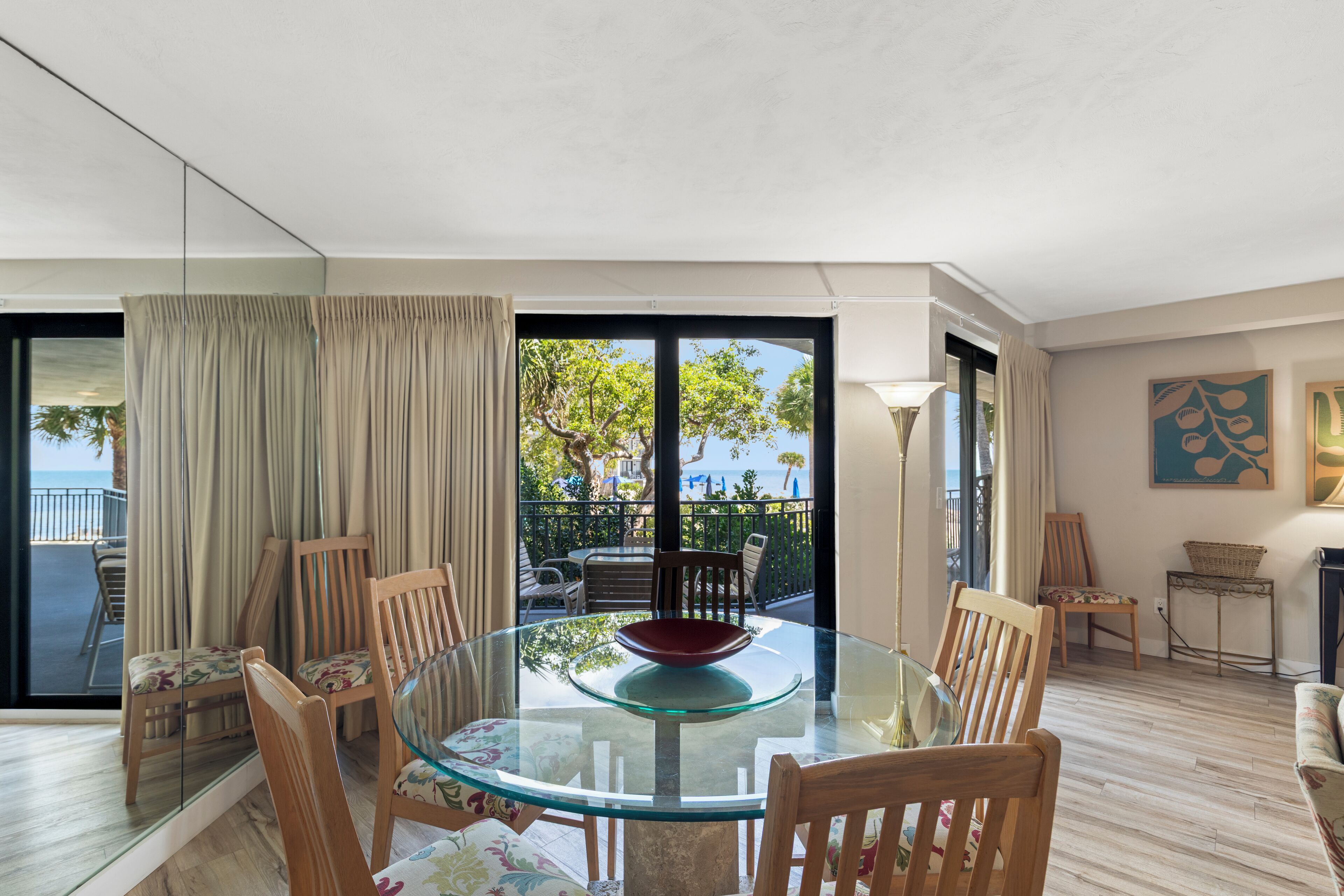 Un comedor moderno con una mesa de vidrio y sillas de madera, vista al exterior y un balcón con barandilla.