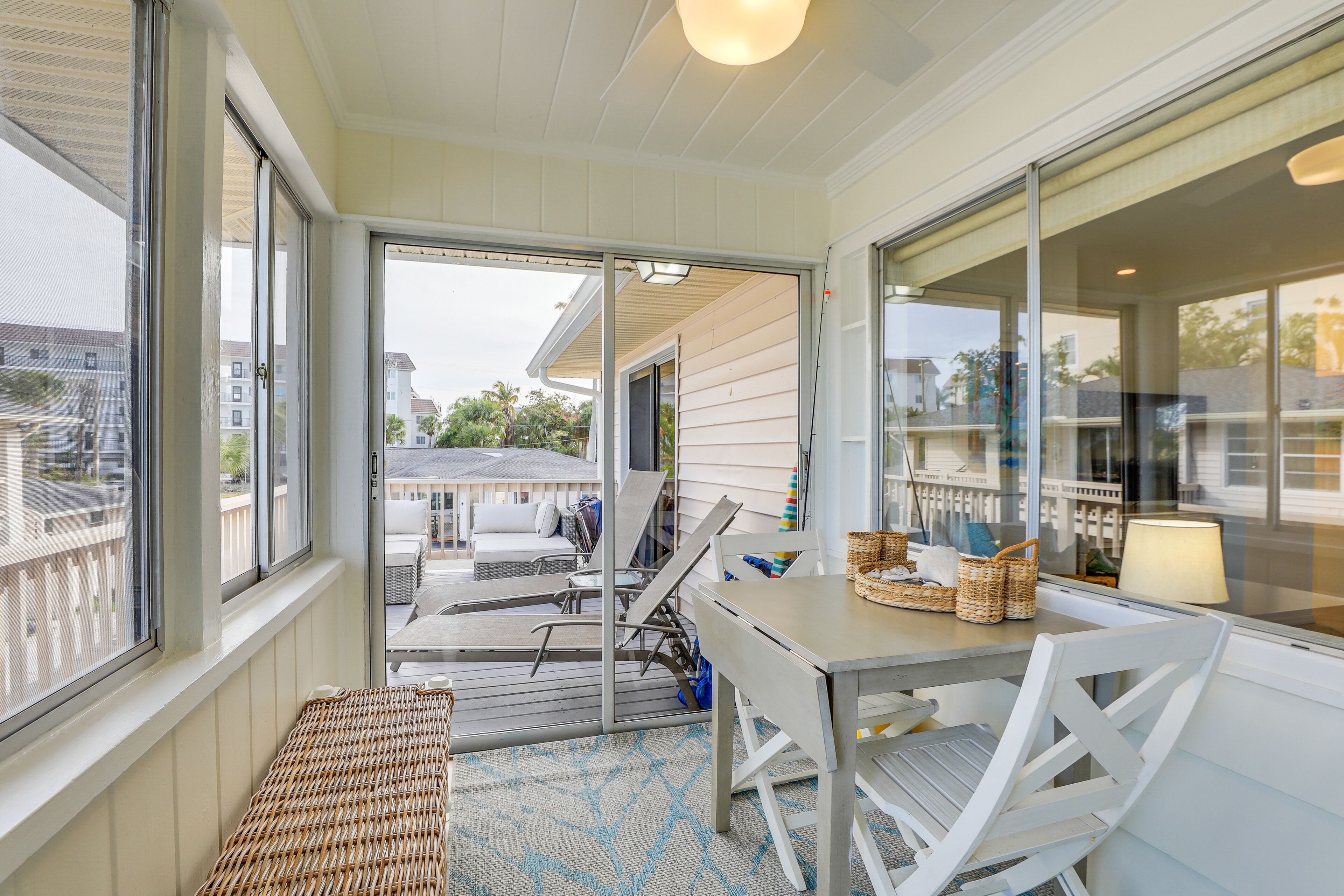 A balcony with a table, chairs, and a wicker bench.