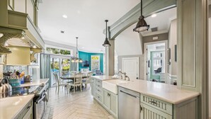 Una cocina amplia con una isla central, iluminación colgante y vistas al exterior.