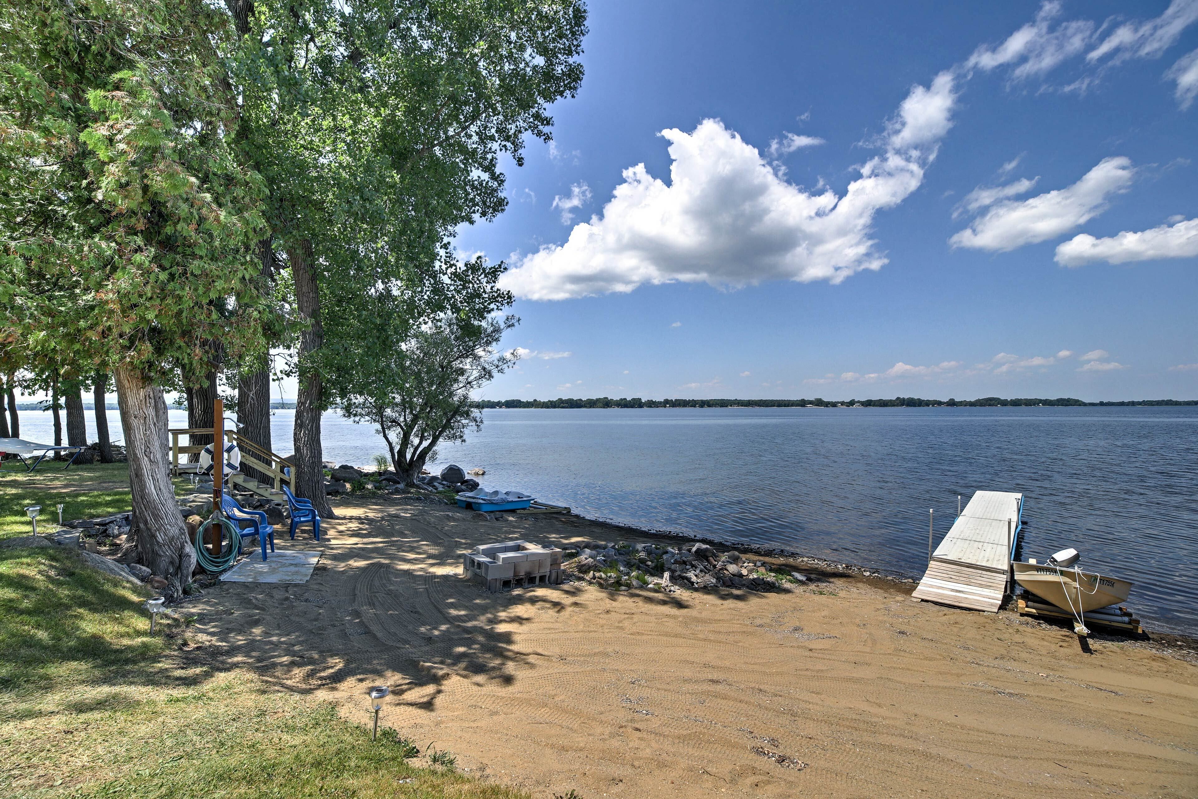 A lakeside campsite with a dock, a covered seating area, and a sandy beach.