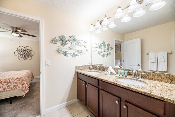 A bathroom with a double sink vanity, a ceiling fan, decorative wall art, and a large mirror. - 8BR ChampionsGate Villa | Theater & Themed Rooms (Davenport)