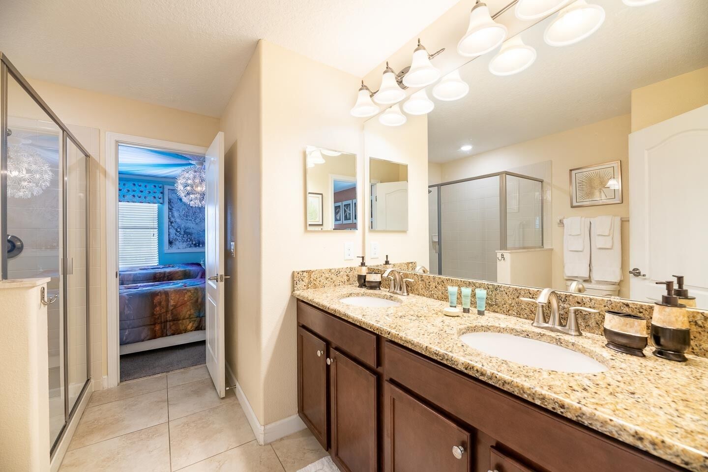 A bathroom with a double sink vanity, a large mirror, and a shower area.