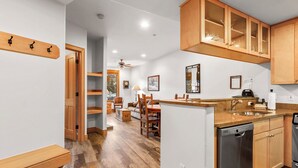 Une cuisine avec des meubles de rangement en bois, un lave-vaisselle et un coin repas comprenant des chaises et une table.
