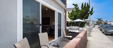 A patio area with outdoor seating, a grill, and a view of the street.