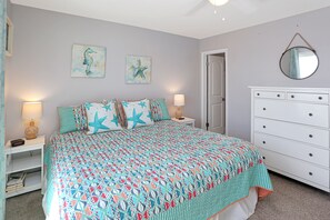 Une chambre à coucher comprenant un lit, des tables de chevet, une commode et des œuvres d’art murales.