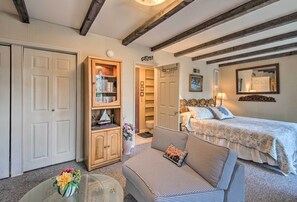 Relax in a traditional room with a checkered sofa, wooden cabinet, and glass coffee table, featuring a comfortable bed and mirror.