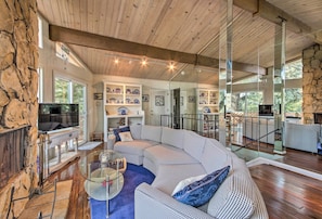 Relax in this spacious living area with a high ceiling, featuring a curved sofa, fireplace, and modern TV.