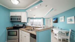 Une cuisine moderne dotée d’appareils électroménagers en acier inoxydable, de meubles blancs et d’un mur d’accent de couleur turquoise.