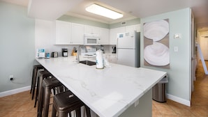 A modern kitchen with white cabinets, a marble countertop, and a stainless steel sink.