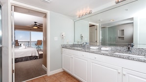 A modern bathroom with a large mirror, white cabinets, and a granite countertop.