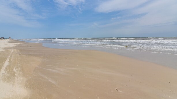 A beach with a wide sandy shore and gentle waves. - Walk to Gulf: Surfside Beach Home w/ Deck (Surfside Beach)