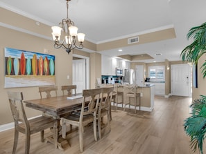 A spacious kitchen with white cabinets, a wooden dining table, and a chandelier.