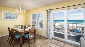 A dining area with a wooden table set for four, a chandelier, and a large window with a view of the beach. - IBR 3006: Sandy Smiles - Unbeatable Location, Unmatched Oceanfront Views! (Fort Walton Beach)