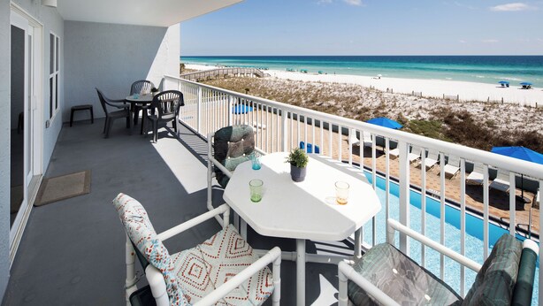 A balcony with a table and chairs, a pool, and a beach view. - IBR 3006: Sandy Smiles - Unbeatable Location, Unmatched Oceanfront Views! (Fort Walton Beach)