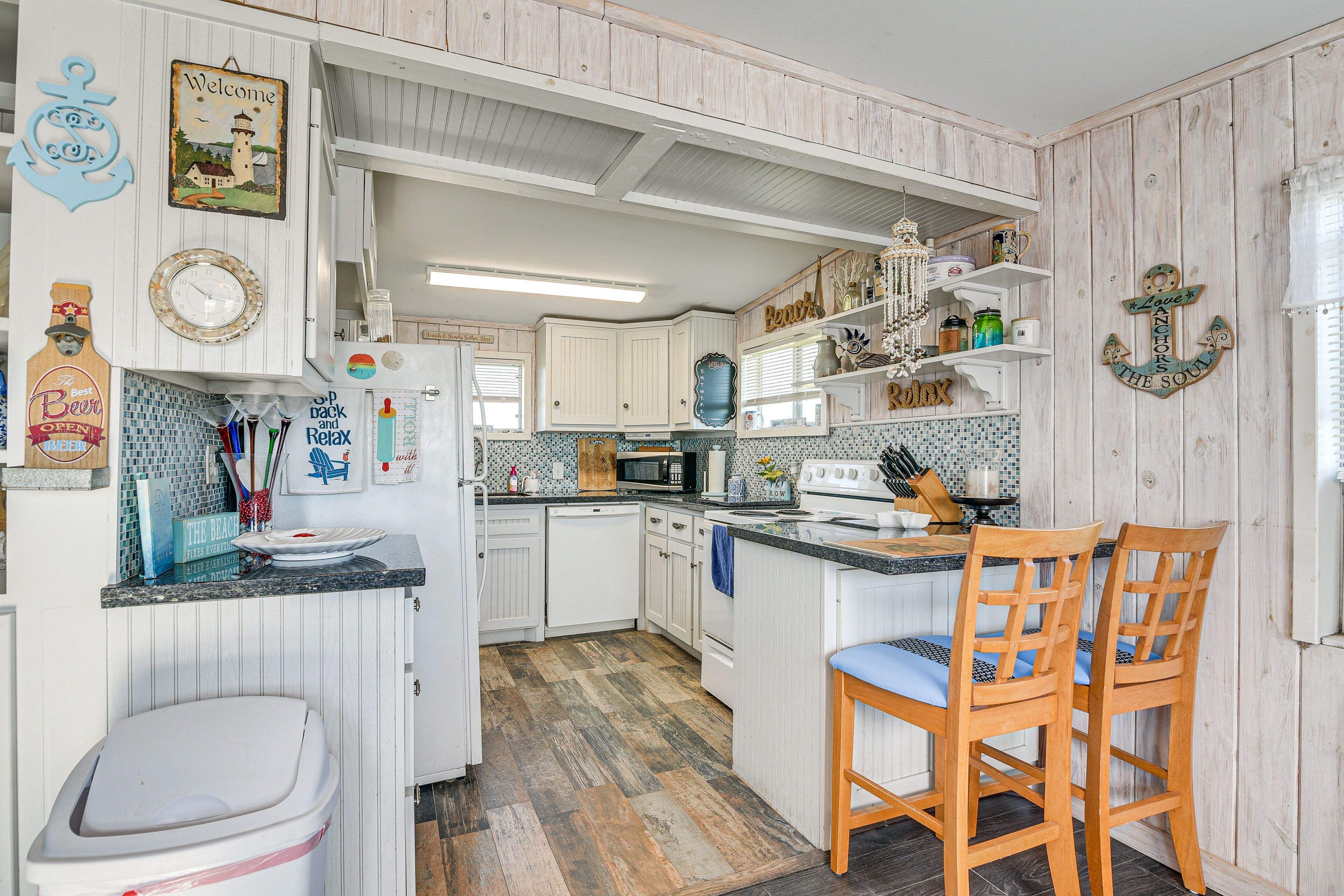 Une cuisine compacte avec des meubles blancs, un four à micro-ondes, un évier et un îlot central en bois avec des chaises.