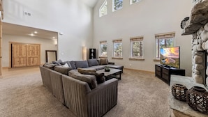 A spacious living room with a sectional sofa, a fireplace, and multiple windows.