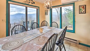 A dining room with a table set for six, large windows with a mountain view, a chandelier, and an air conditioning unit. - Secluded Home w/ Views in Burnsville: Hike & Ski! (Burnsville)