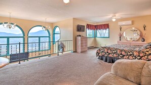 A bedroom with a large window, a balcony, a bed with floral bedding, a dresser, and a television. - Secluded Home w/ Views in Burnsville: Hike & Ski! (Burnsville)