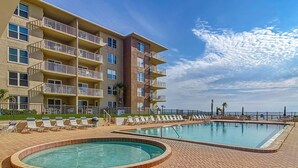 A hotel with a pool area, multiple balconies, and a view of the ocean.
