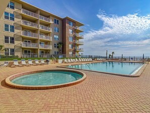 A hotel with a pool area, multiple balconies, and a view of the ocean.
